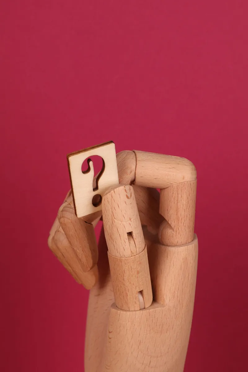 Point d&rsquo;interrogation tenu par une main en bois
