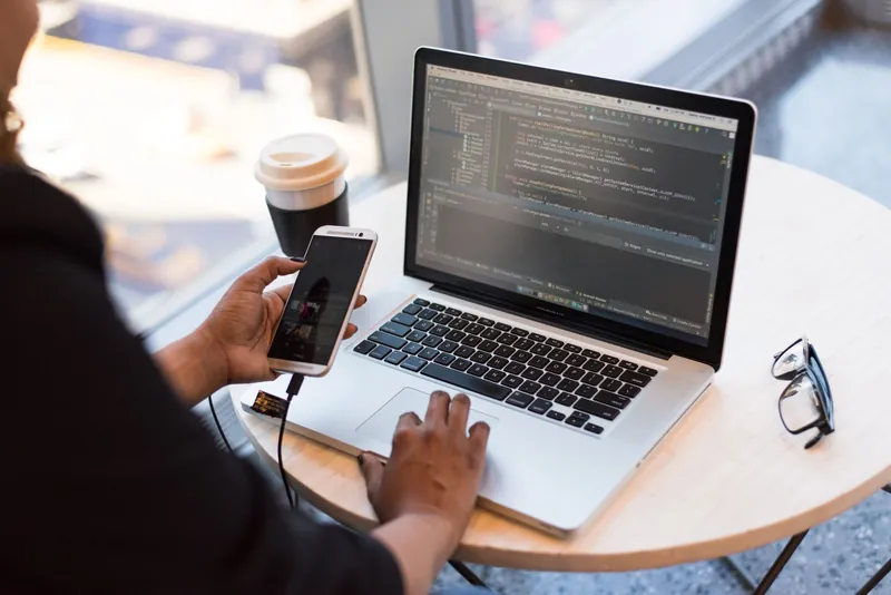 MacBook Pro affichant du code, iPhone en main