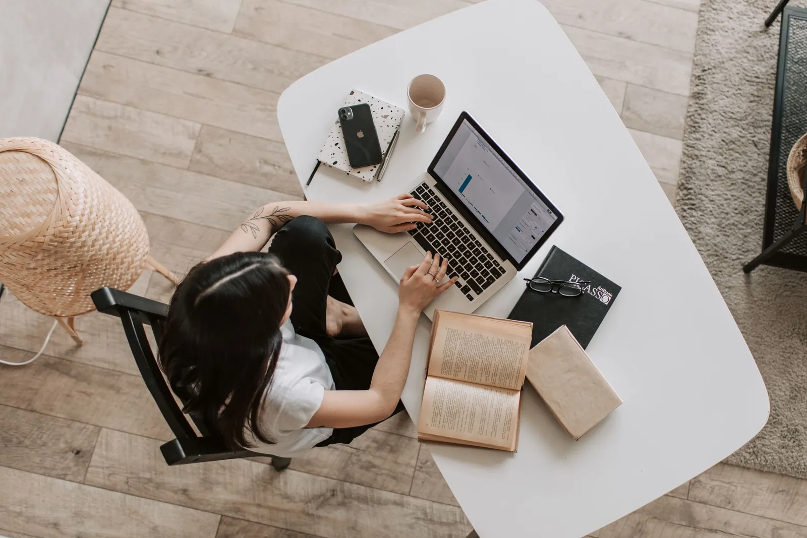 Personne apprenant sur son ordinateur portable, entourée de livres